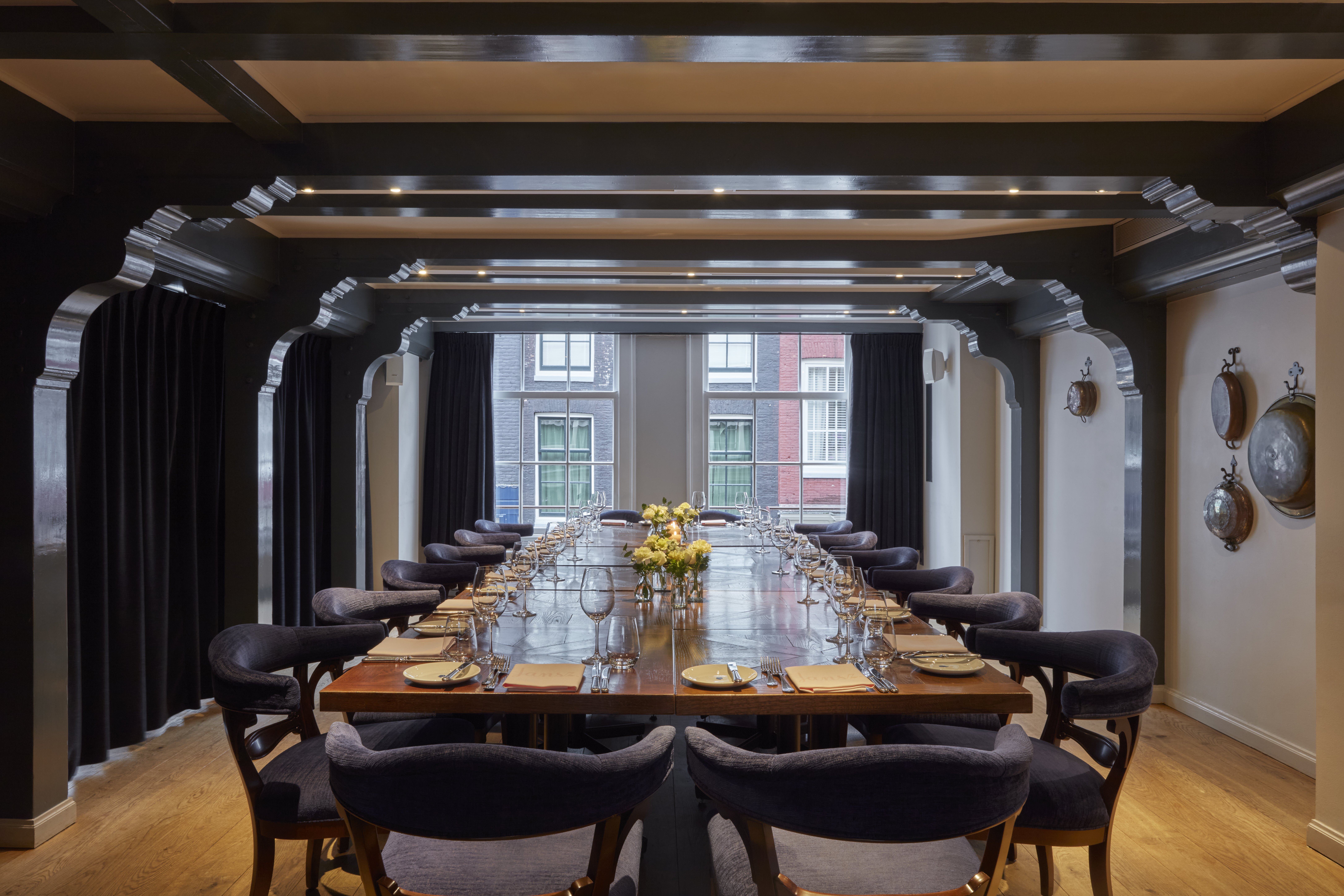 A beautifully set private room with a long wooden table, elegant blue chairs, and a flower centerpiece under soft lighting.