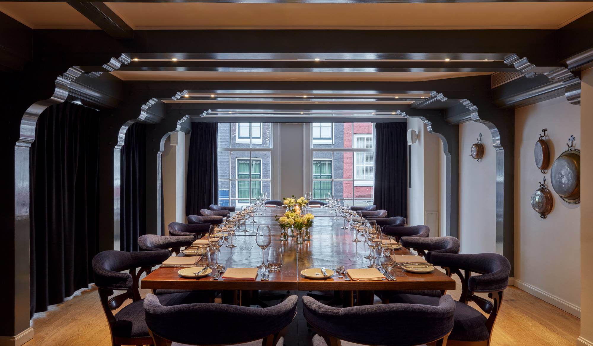 A beautifully set private room with a long wooden table, elegant blue chairs, and a flower centerpiece under soft lighting.